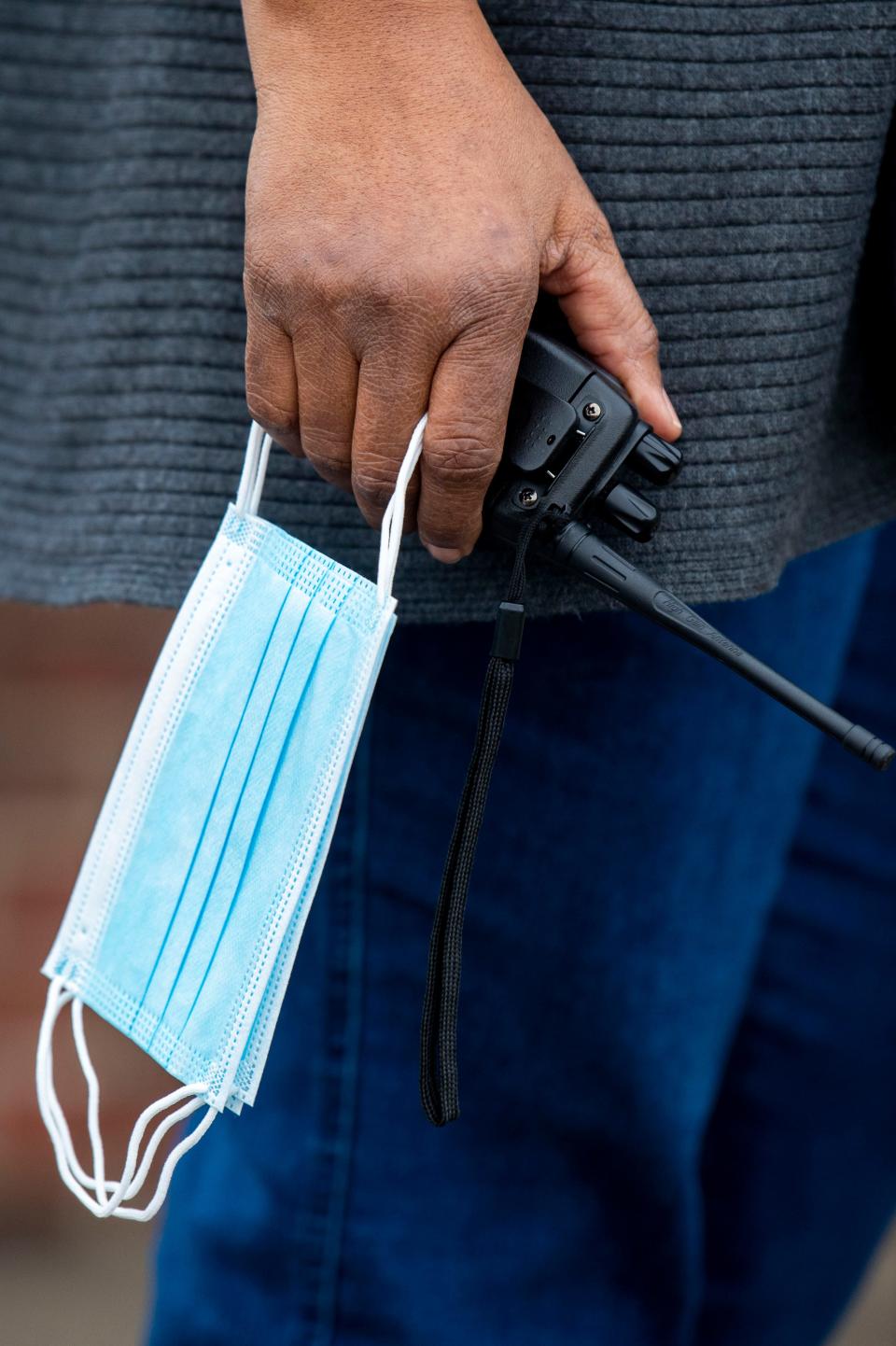 Bonita Perkins holds spare masks and a walkie-talkie in her hand as she greets students on the first day back to in-person learning at DuPont Taylor Middle School on Friday, Feb. 26, 2021 in Nashville, Tenn.