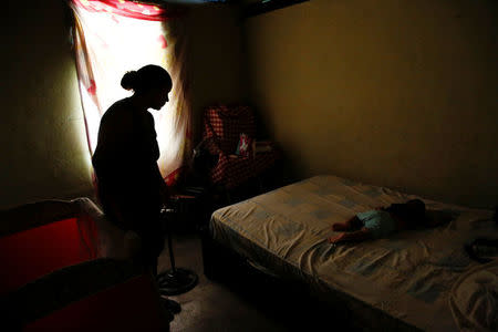 Yelis Toussaint looks to her son Jhonanyel, while he sleeps on a bed, before her sterilization surgery at their home in Charallave, Venezuela July 7, 2016. REUTERS/Carlos Garcia Rawlins