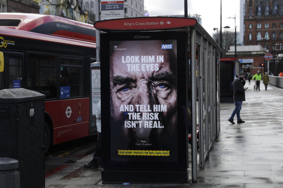 FILE - In this Jan. 29, 2021, file photo, a coronavirus information sign is displayed by a bus stop in London during England's third national lockdown since the coronavirus outbreak began. Psychology experts offer several suggestions for talking to friends and family who believe conspiracy theories about COVID-19. Instead of lecturing or mocking, listen and ask them why they believe what they believe. (AP Photo/Matt Dunham, File)