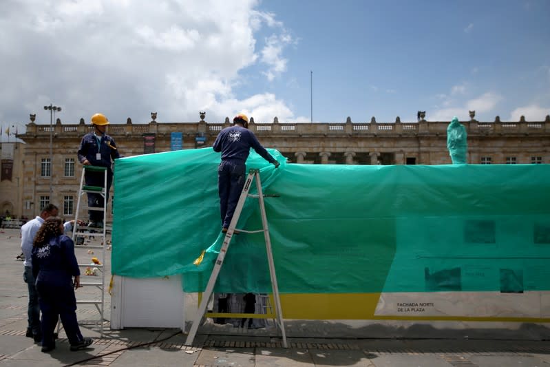 Workers cover the statue of Simon Bolivar in Bogota with plastic, one day before a national strike in Bogota