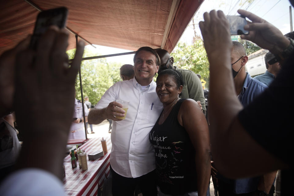 Brazil's President Jair Bolsonaro, left, poses for a photo with a supporter after voting during run-off municipal elections in Rio de Janeiro, Brazil, Sunday, Nov. 29, 2020. Bolsonaro, who sometimes has embraced the label "Trump of the Tropics," said Sunday he'll wait a little longer before recognizing the U.S. election victory of Joe Biden, while echoing President Donald Trump's allegations of irregularities in the U.S. vote. (AP Photo/Silvia Izquierdo)