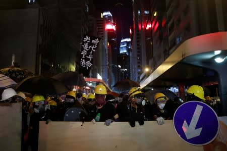 Demonstrators hold makeshift shields as they face riot police during a protest against police violence in Hong Kong