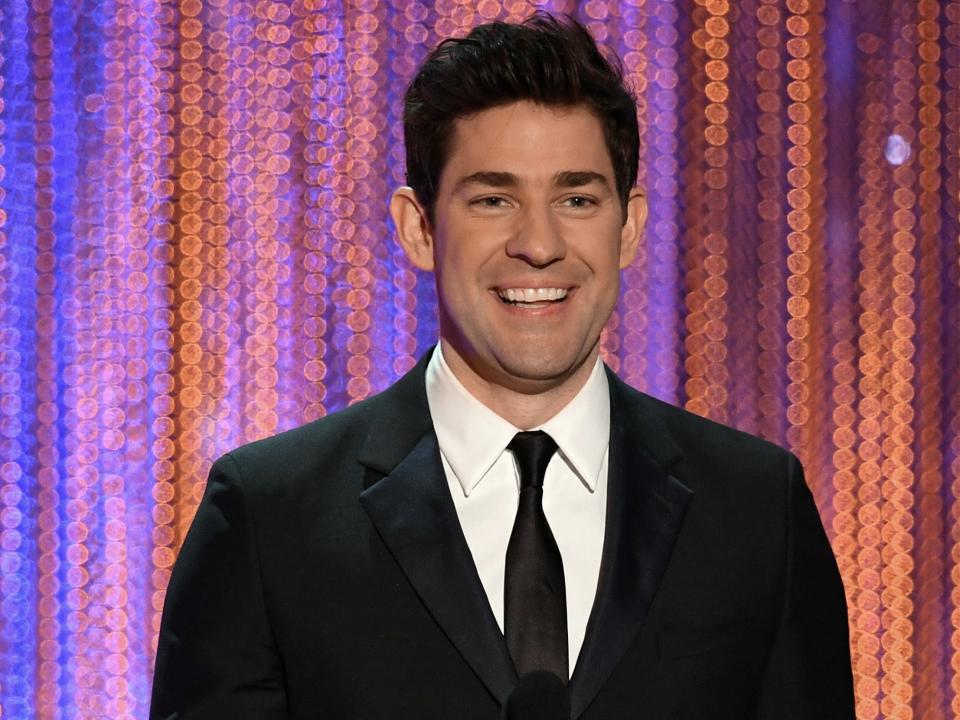 John Krasinski wears a black suit and smiles