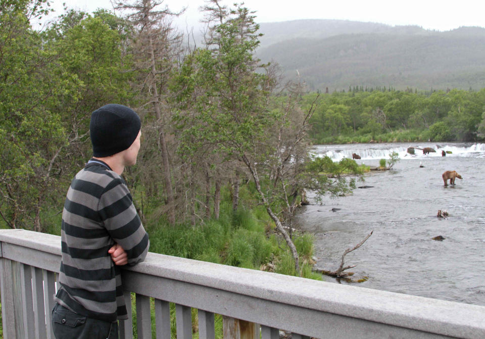 In this photo taken July 4, 2013, in Katmai National Park and Preserve, Alaska, is longtime bear cam viewer Shawn Turner looking at bears in the Brooks River. The Portland, Ore., man spent his two week vacation camping out at the park. It's expensive and difficult to reach the park about 250 miles west of Anchorage, and explore.org has again set up high definition webcams to livestream the daily activities of the bears at the park. (AP Photo/Mark Thiessen)