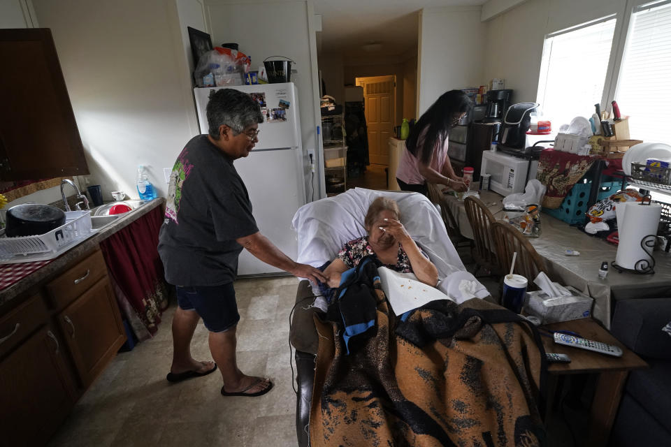 Irene Verdin tends to her sister-in-law Vorina Roussell, who is bed-bound, inside a trailer she is living in, next to her home that was heavily damaged by Hurricane Ida nine months before, along Bayou Pointe-au-Chien, La., Tuesday, May 24, 2022. (AP Photo/Gerald Herbert)