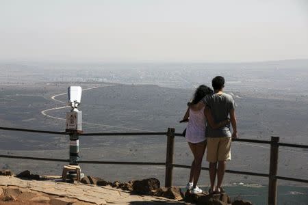 A couple look at the Syrian area of Qunietra at Mount Bental, an observation post in the Israeli-occupied Golan Heights near the ceasefire line between Israel and Syria August 21, 2015. REUTERS/Baz Ratner