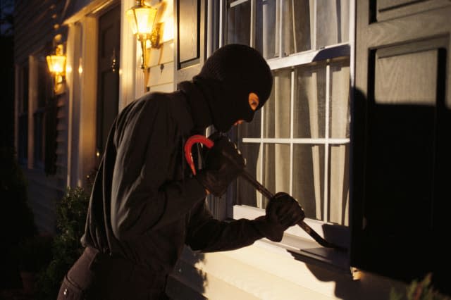 Burglar trying to pry open window on house