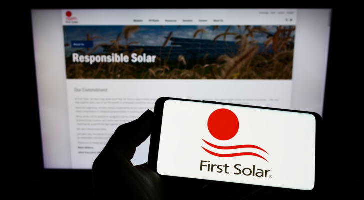 Person holding smartphone with logo of US renewable energy company First Solar Inc. (FSLR) on screen in front of website. Focus on phone display. Unmodified photo. Green energy stocks
