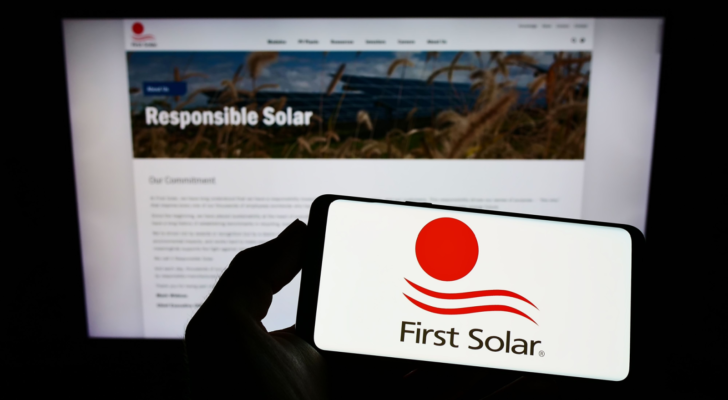 Person holding smartphone with logo of US renewable energy company First Solar Inc. (FSLR) on screen in front of website. Focus on phone display. Unmodified photo.