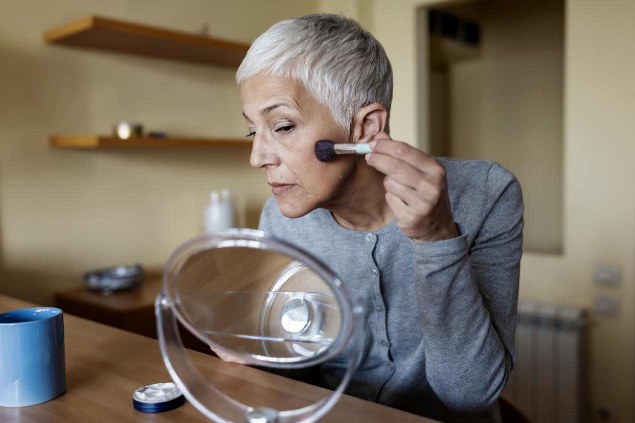 Good Looking Senior Woman Doing Makeup In Front Of Mirror