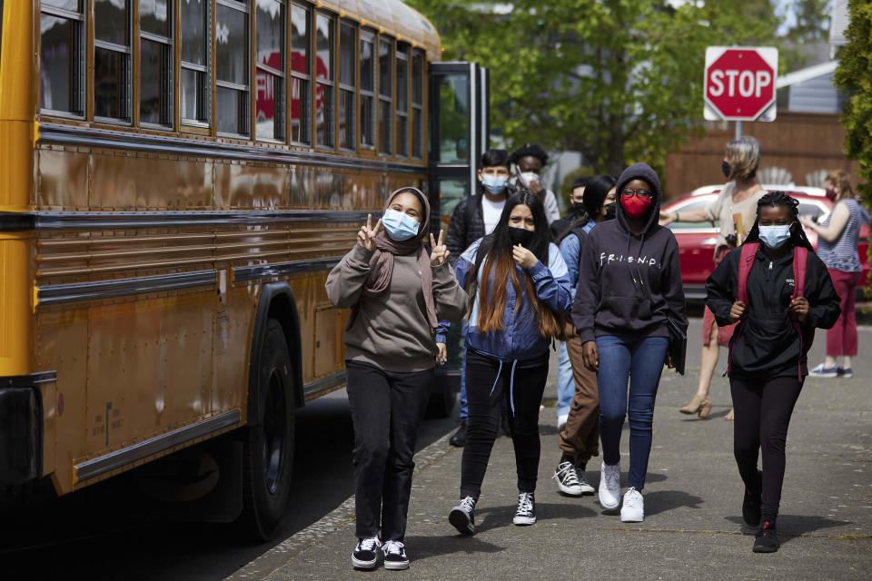 FILE — Students get off the bus at Roseway Heights Middle School on the first day of in-person hybrid learning, April 19, 2021, in Portland, Ore. The governors of Connecticut, Delaware, New Jersey and Oregon this week announced plans to lift mask mandates in schools by the end of February or March, as COVID-19's omicron surge fades. (Craig Mitchelldyer/AP Images for Portland Public Schools, File)