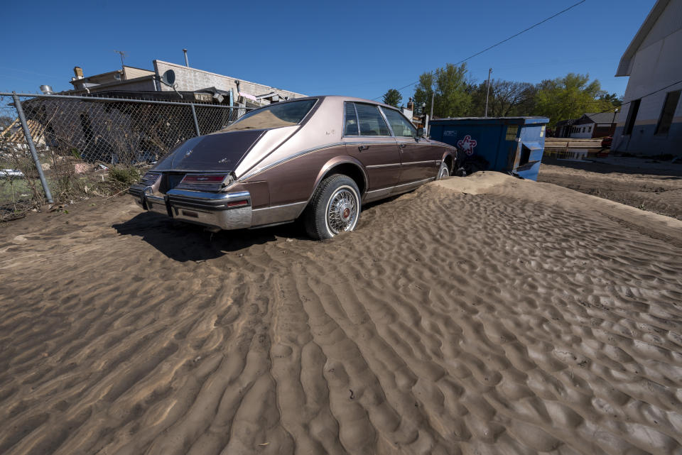 A Cadillac sits in a pile of sand as residents and business owners dig out after flooding swept through the town of Sanford, Thursday, May 21, 2020. Senior citizens are among the scores of displaced people staying in shelters after flooding overwhelmed two dams, submerged homes and washed out roads in Central Michigan. (David Guralnick/Detroit News via AP)
