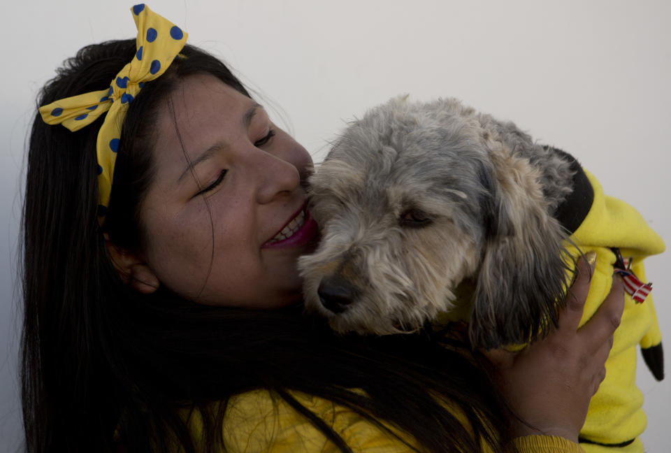 Una boliviana y su mascota lucen disfraces iguales para asistir a una misa celebrada en honor a San Roque, patrono de los canes en El Alto, Bolivia, el jueves 16 de agosto de 2018. (AP Foto/Juan Karita)