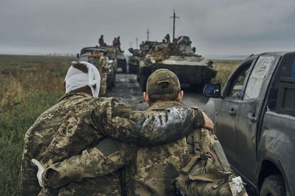 FILE - A Ukrainian soldier helps a wounded fellow soldier on the road in the freed territory in the Kharkiv region, Ukraine, Monday, Sept. 12, 2022. As milestones go, the first anniversary of Russia's invasion of Ukraine is both grim and vexing. It marks a full year of killing, destruction, loss and pain felt even beyond the borders of Russia and Ukraine. (AP Photo/Kostiantyn Liberov, File)