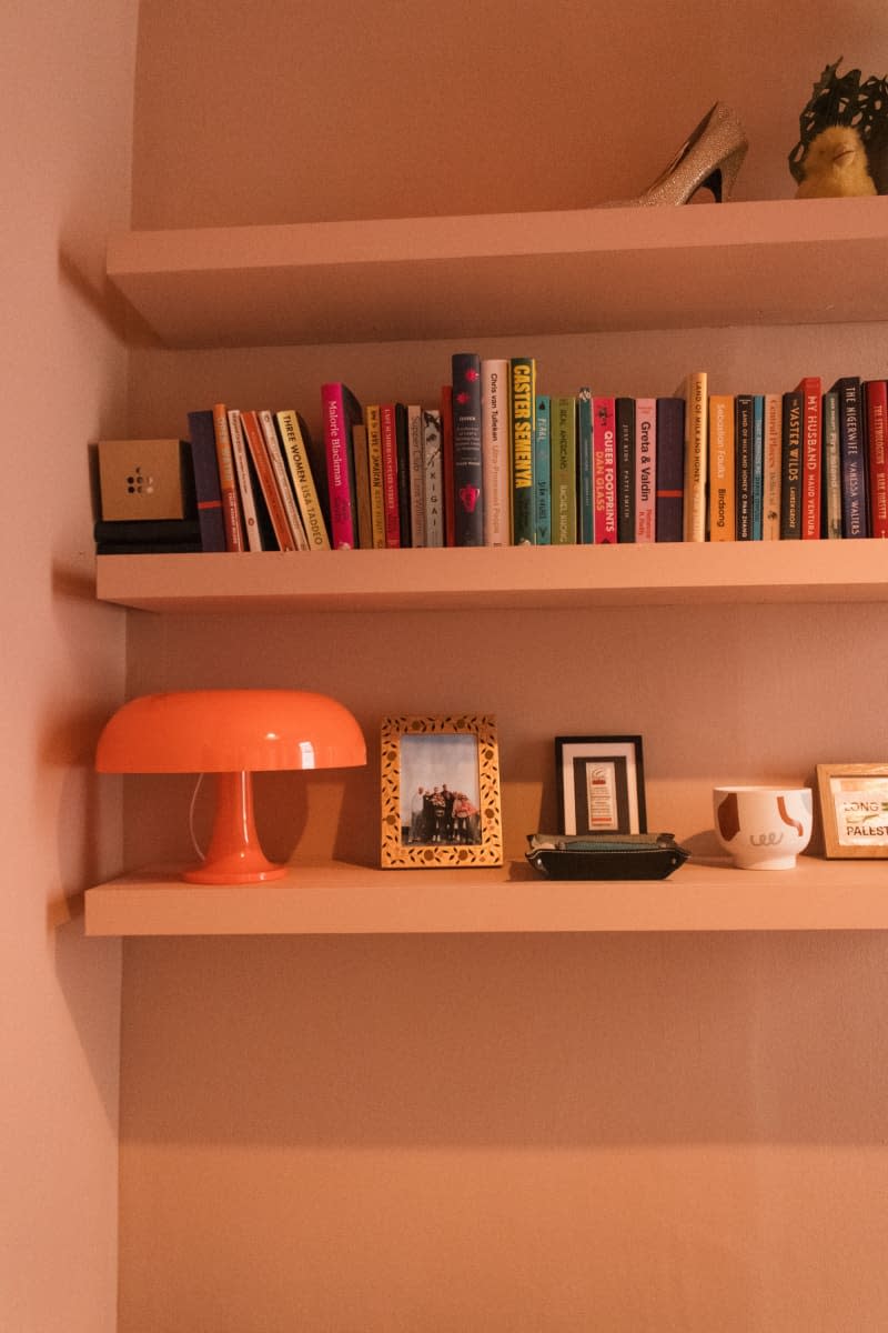 Bookshelf with books and glass lamp.