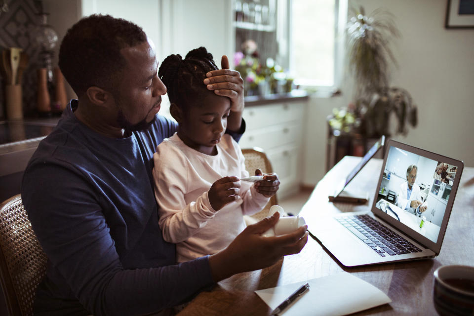 Close up of a father and daughter having a video call with their doctor