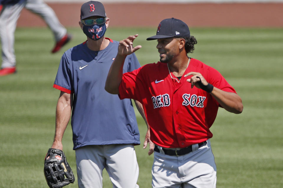 Boston Red Sox's Xander Bogaerts, right, runs past Interim Manager Ron Roenicke during baseball training camp at Fenway Park, Tuesday, July 7, 2020, in Boston. (AP Photo/Elise Amendola)