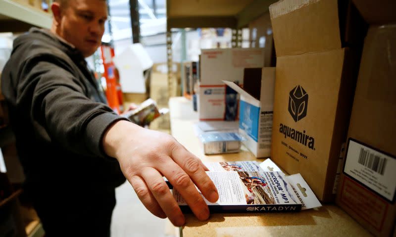 An employee grabs water purification tablets that kill viruses to go into a personal protection and survival equipment kits ordered by customers preparing against novel coronavirus, at Nitro-Pak in Midway