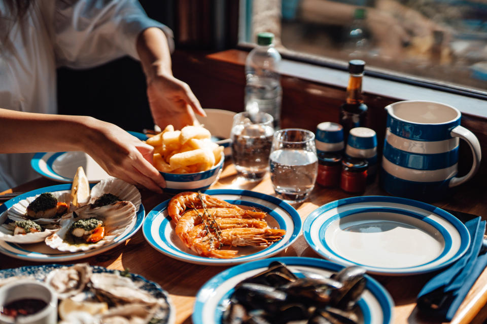 A person putting down a bowl of food onto a table full of more food