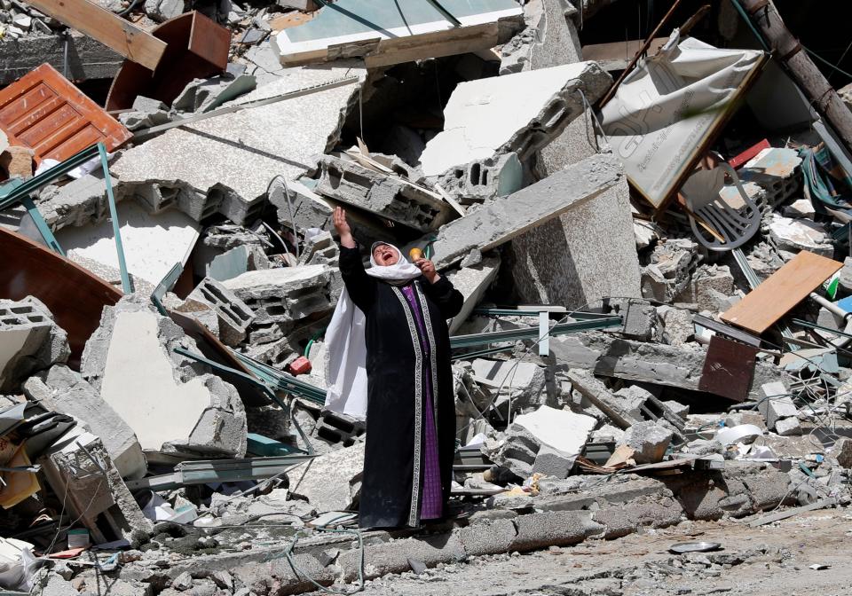  May 16, 2021:  A woman reacts while standing near the rubble of a building that was destroyed by an Israeli airstrike on Saturday that housed The Associated Press, broadcaster Al-Jazeera and other media outlets, in Gaza City.