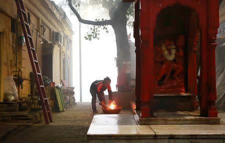 A man lights a bonfire on the banks of Yamuna river on a cold winter morning in New Delhi, December 24, 2018. REUTERS/Adnan Abidi