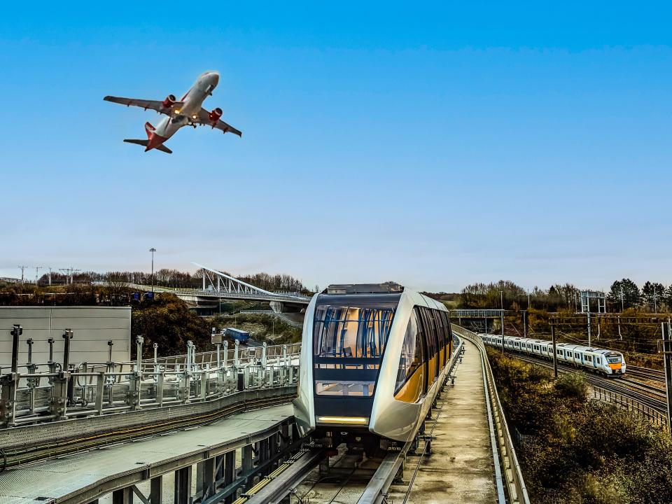 A plane flies over the Luton DART train and tracks