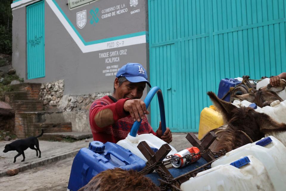 Isidro Varela, 50, fills a container with water at a free public well, in Pueblo of Santa Cruz Acalpixa, Xochimilco on the outskirts of Mexico City, Saturday, Oct.7, 2023. (AP Photo/Ginnette Riquelme)