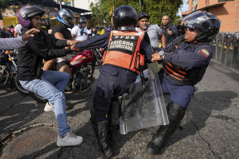 Un manifestante se pelea con la policía durante manifestaciones contra los resultados oficiales de las elecciones que declaran la reelección del presidente Nicolás Maduro, el día después de la votación en Caracas.