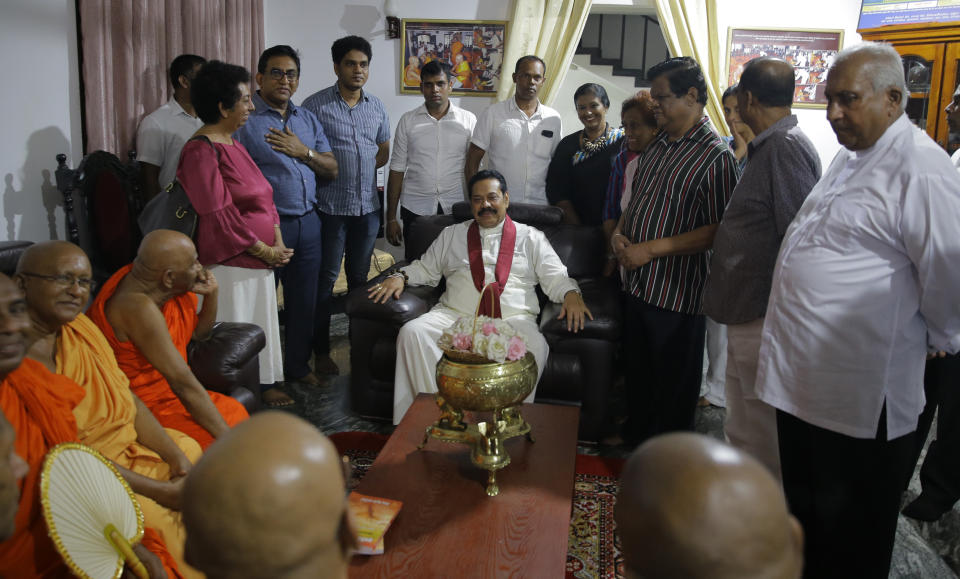 Newly appointed Sri Lankan Prime Minister Mahinda Rajapaksa, center, talks with his supporters at a Buddhist temple in Colombo, Sri Lanka, Friday, Oct. 26, 2018. Sri Lankan President Maithripala Sirisena has sacked the country's prime minister and replaced him with a former strongman, state television said Friday. (AP Photo/Eranga Jayawardena)