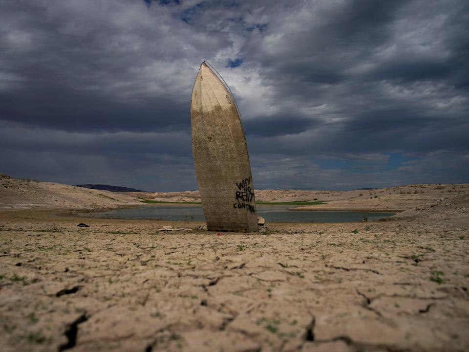 A formerly sunken boat sits upright into the air with its stern stuck in the mud along the shoreline of Lake Mead on June 22, 2022.