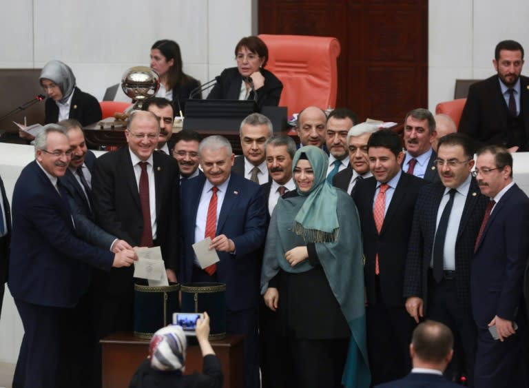 Turkey's Prime Minister Binali Yildirim (C) accompanied by lawmakers vote following a parliament debate on January 21, 2017 on proposed amendments to the country's constitution