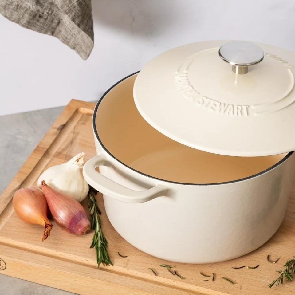 Martha Stewart Dutch oven on a wooden board with garlic, shallots, and rosemary nearby