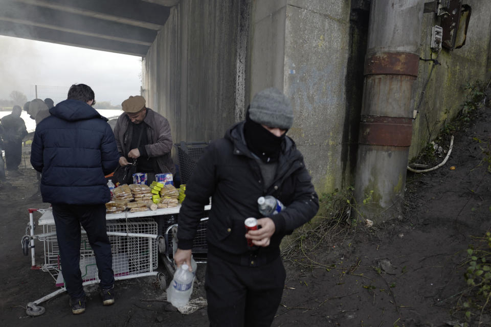 A migrant buys goods in a makeshift camp in Calais, northern France, Saturday, Nov. 27, 2021. At the makeshift camps outside Calais, migrants are digging in, waiting for the chance to make a dash across the English Channel despite the news that at least 27 people died this week when their boat sank a few miles from the French coast. (AP Photo/Rafael Yaghobzadeh)