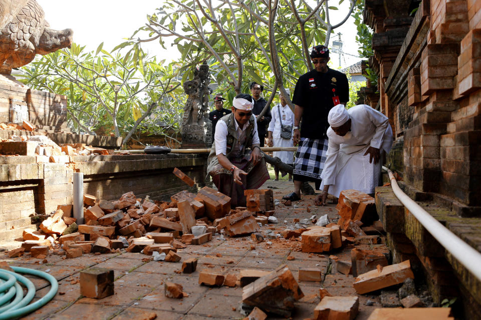 Balinese man collect stones from a damaged temple in Bali, Indonesia on Tuesday following the earthquake.