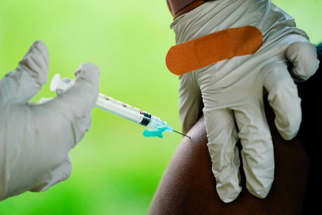 A health worker administers a dose of a Pfizer COVID-19 vaccine.