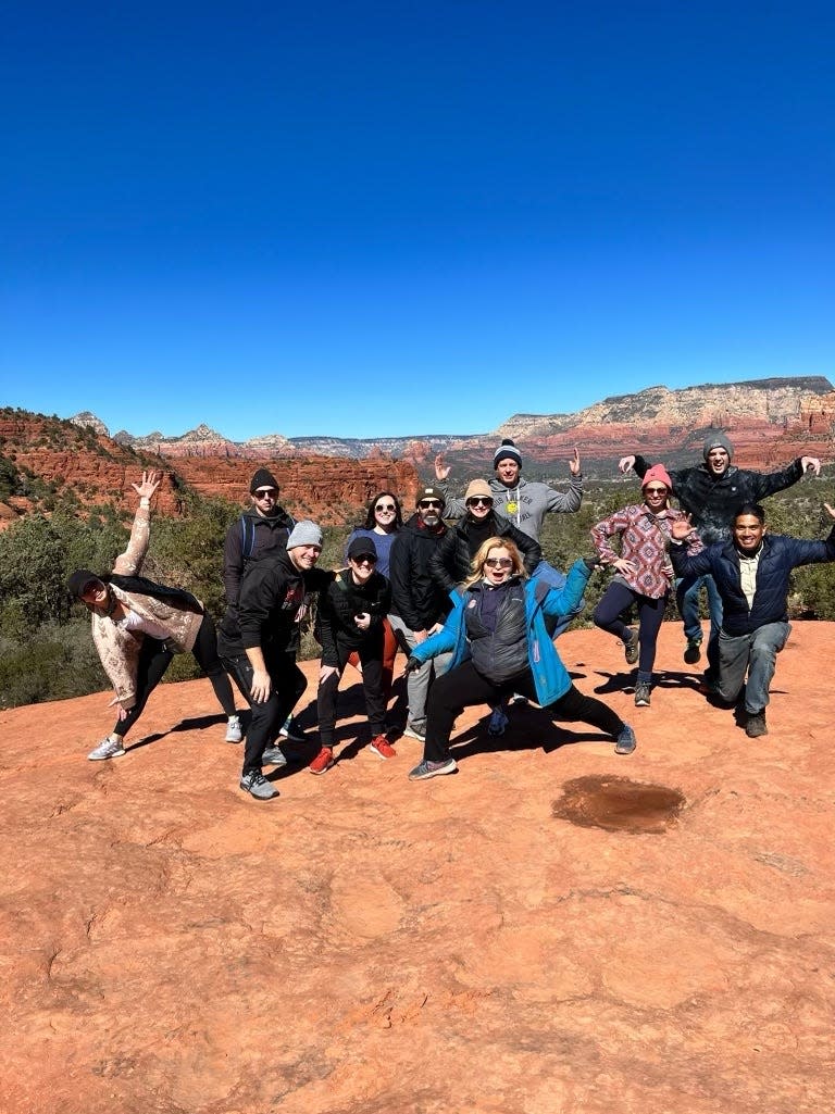 A group of people posing at the top of a scenic hike.