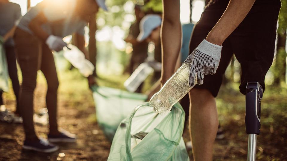 Group of multi-ethnic people, people with differing abilities , volunteers with garbage bags cleaning park area.