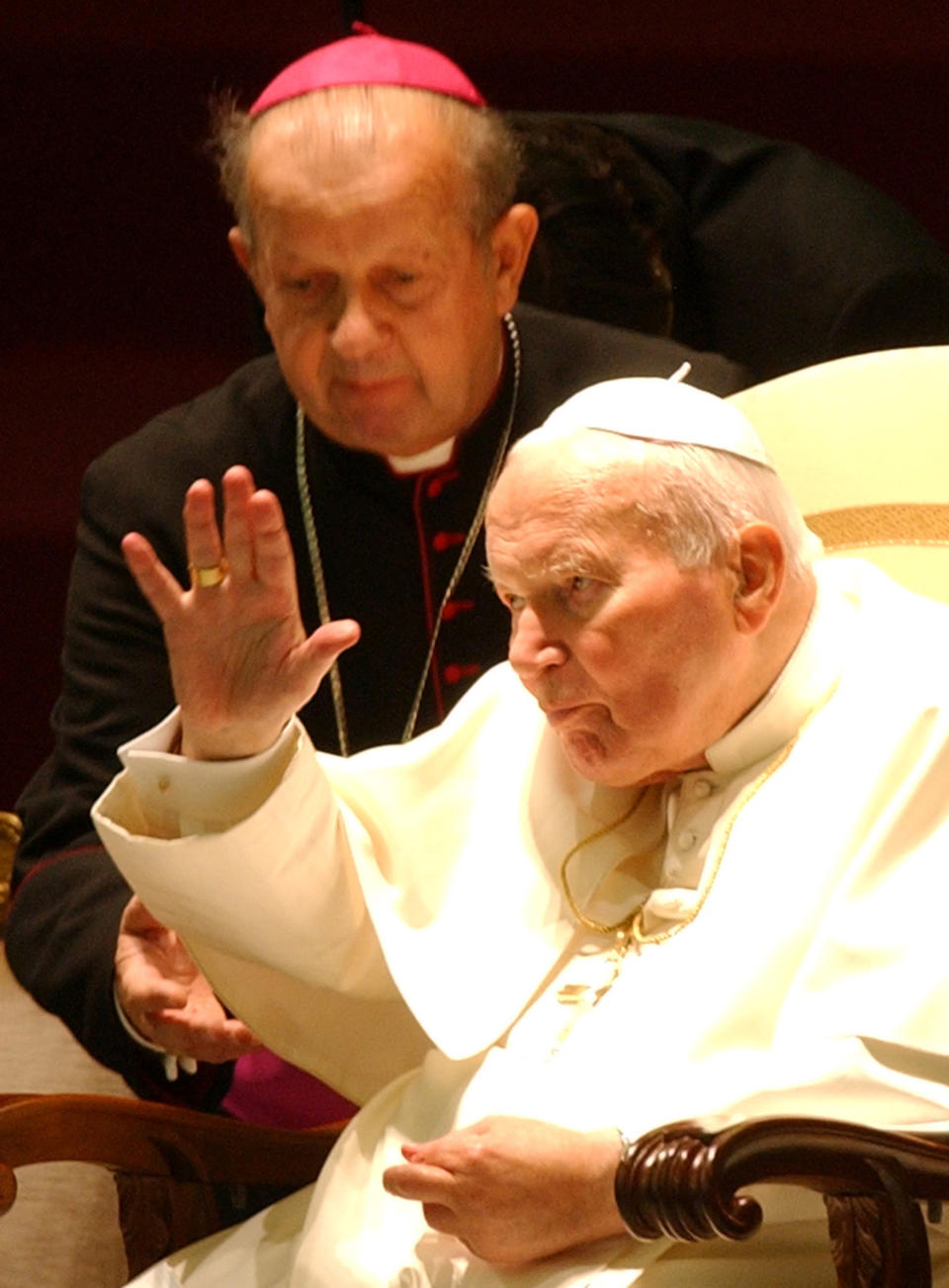 FILE - In this Oct. 16, 2003 file photo Archbishop Stanislaw Dziwisz assists a waving Pope John Paul II during a special audience in the Paul VI Hall at the Vatican. Poles are divided between praise and condemnation of John Paul II’s secretary for publishing the late pope’s personal notes against his last will and testament. John Paul ordered the notes burned after his death and put his trusted confidant, the Rev. Dziwisz, in charge of the task. To everyone’s surprise, Dziwisz, now a cardinal, said recently that he “did not have the courage” to destroy the notes and is having them published as a precious insight into the inner life of the beloved pontiff, who will be declared a saint in April. (AP Photo/Plinio Lepri, File)