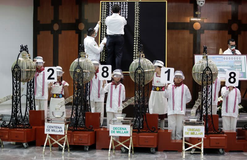 Children hold signs with numbers during a lottery raffle for the value of the last president's luxury plane at the National Lottery building in Mexico City