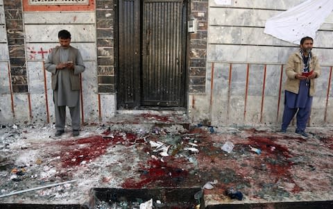 Afghans stand outside a voter registration center after the attack that killed at least 48 - Credit: AP Photo/Rahmat Gul