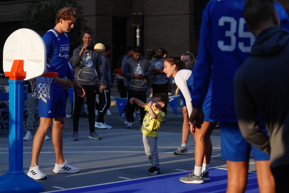 Drake men’s guard Tucker Devries and women’s guard Megan Meyer shoot hoops with Emerson Richter during the Drake Hoops Fest on Court Ave. in 2022. Meyer said she hopes her choice to return to basketball can make a positive impact on young girls.