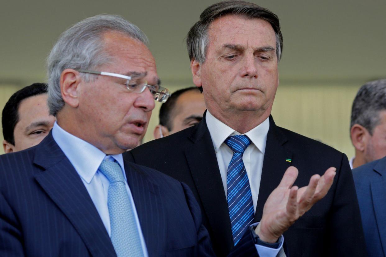 El presidente brasileño, Jair Bolsonaro (d), y el ministro de Economía brasileño, Paulo Guedes (izq.), hablan sobre ayuda financiera para brasileños vulnerables, hoy, en el Palacio Planalto, en Brasilia