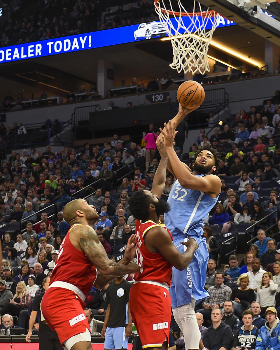 Minnesota Timberwolves center Karl-Anthony Towns (32) goes up to shoot as Houston Rockets guard James Harden, center, and forward P.J. Tucker look on during the first half of an NBA basketball game Friday, Jan. 24, 2020, in Minneapolis. (AP Photo/Craig Lassig)