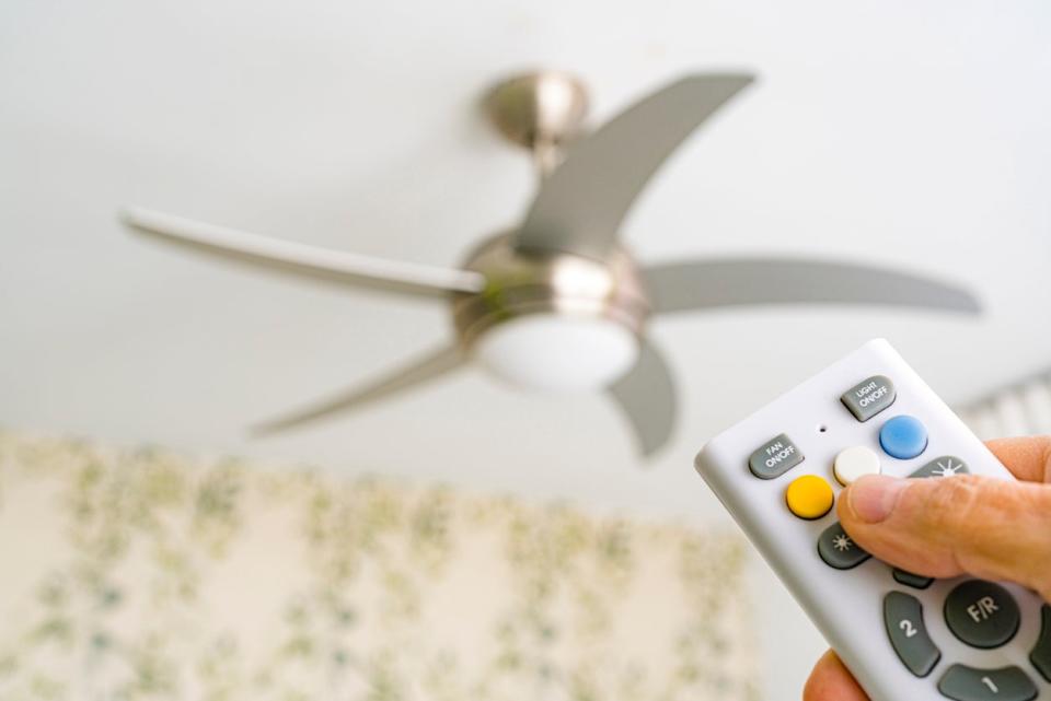 Close up of a hand holding a remote control aiming to ceiling fan. High resolution 42Mp indoors digital capture taken with SONY A7rII and Zeiss Batis 40mm F2.0 CF lens