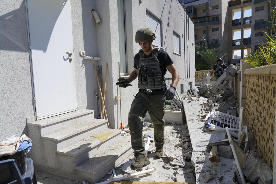Israeli security forces inspect a damaged house after it was hit by a rocket fired from the Gaza Strip in Ashkelon, southern Israel, Friday, Oct. 13, 2023. (AP Photo/Tsafrir Abayov)