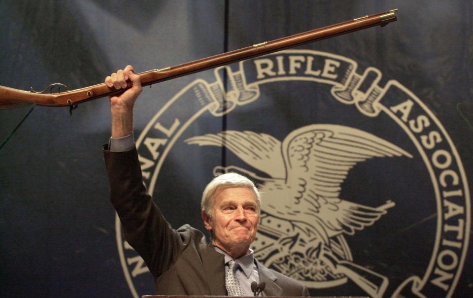 NRA president Charlton Heston holds up a musket in Charlotte, N.C., on May 20, 2000, as he tells members that they can have his gun when they pry it "from my cold dead hands."