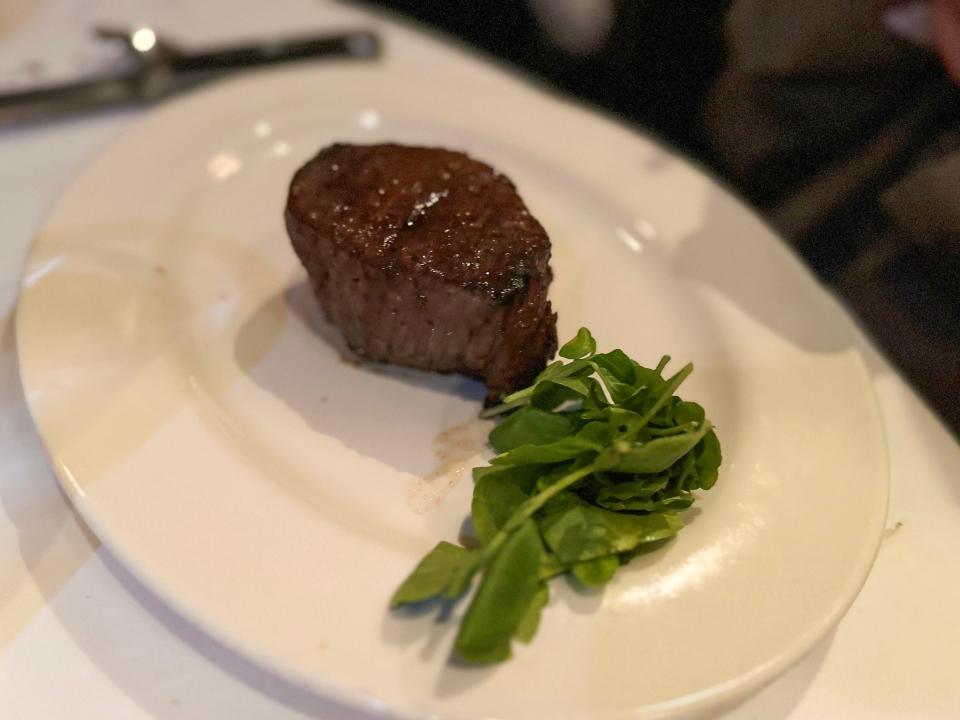 Steak next to pile of greens on plate  at Capital Grille 