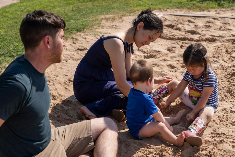 Milly Lee plays in the sand with her children while her husband, Evan Eppinger, looks on. He was scared at first that heart surgery meant he could lose Milly and be raising two children alone.