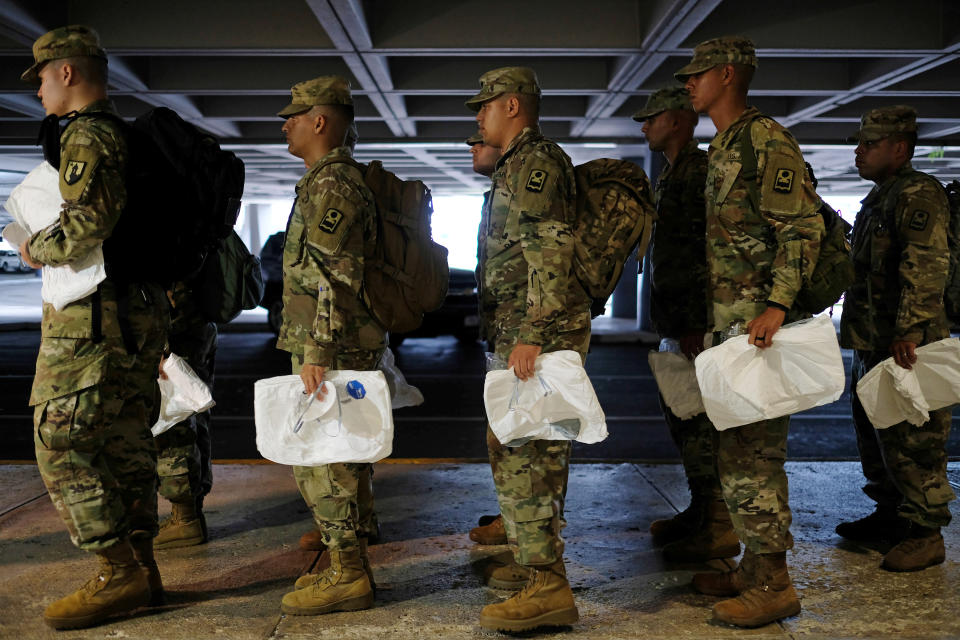 National Guard soldiers receive sterile coveralls to wear before checking the temperature of passengers arriving at Luis Munoz Marin International Airport, amid coronavirus (COVID-19) concerns, in San Juan, Puerto Rico, March 17, 2020. (Ricardo Arduengo/Reuters)