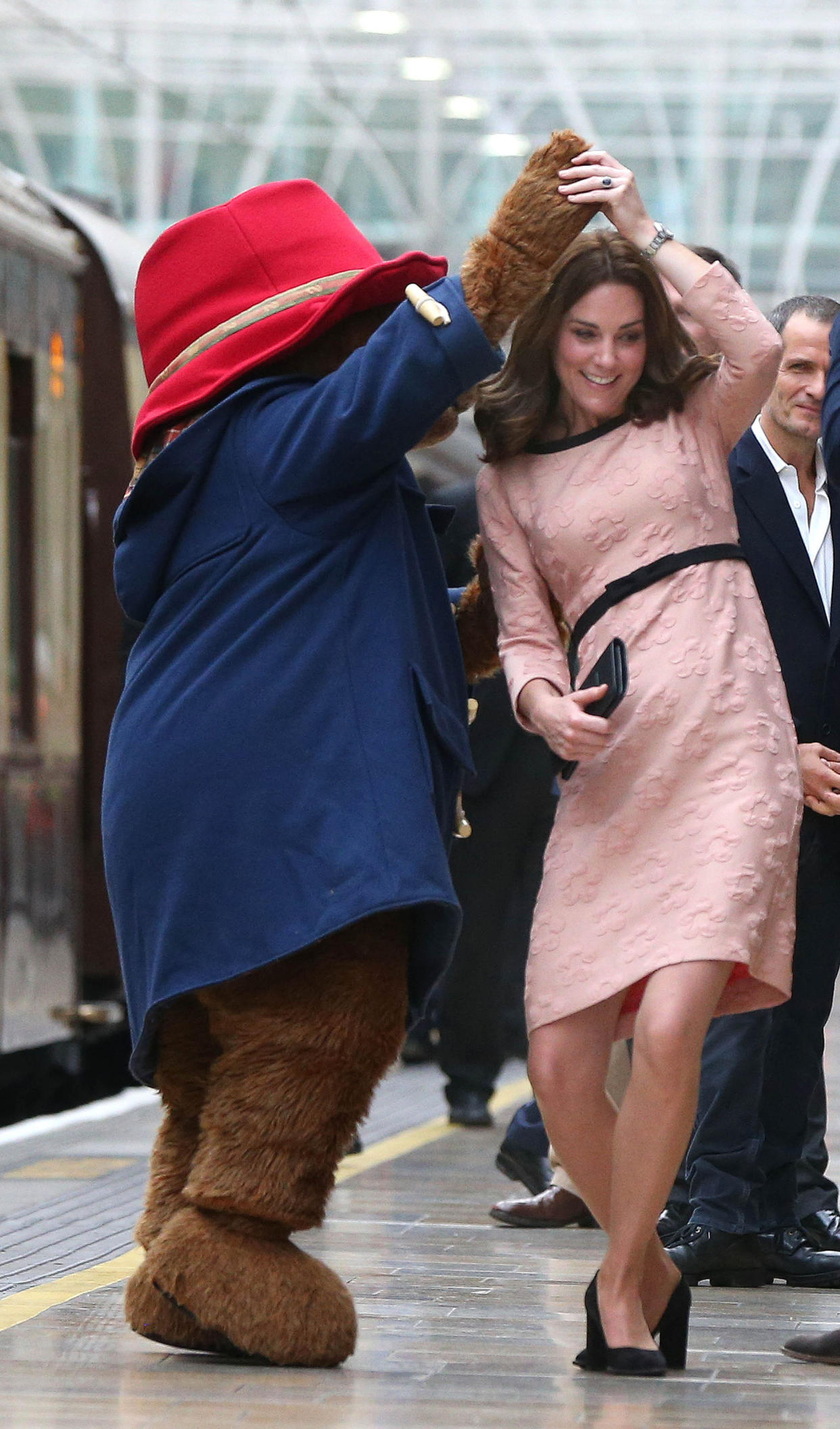 The Duchess of Cambridge dances with a costumed figure of Paddington bear on platform 1 at Paddington Station, London, as she attends the Charities Forum event, joining children from the charities she supports and to meet the cast and crew from the forthcoming film Paddington 2.